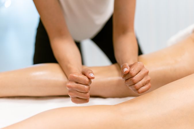 Massage therapist using her forearms to work on her client’s legs