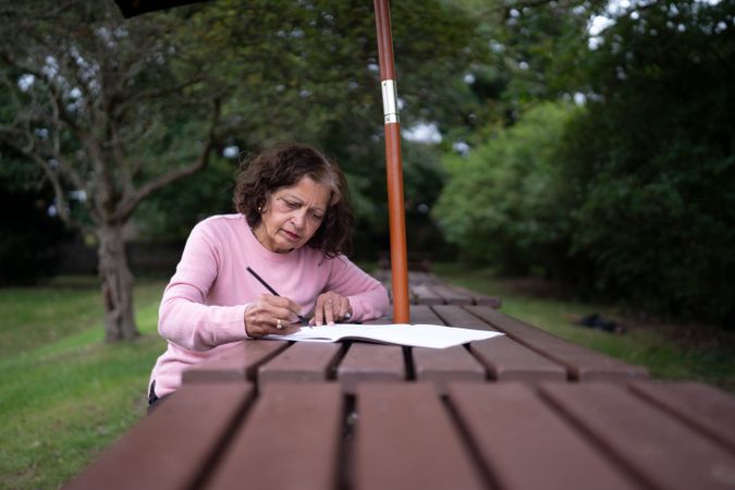 Older woman drawing on park bench