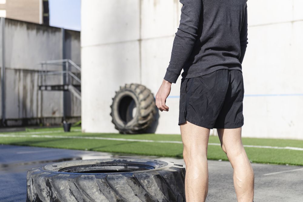 Man training with tire on sports ground