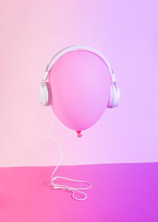 Pink balloon wearing headphones on pink background