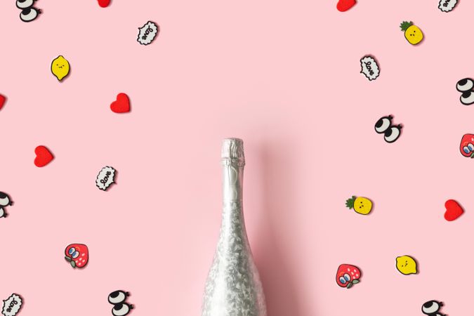 Silver bottle of Champagne on pastel pink background with pop art stickers