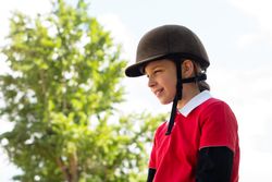 Young equestrian smiling during outdoor riding session.