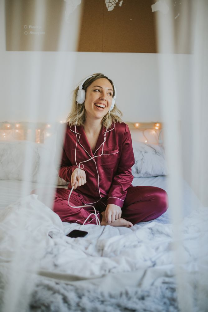Woman with headphones dancing in bed