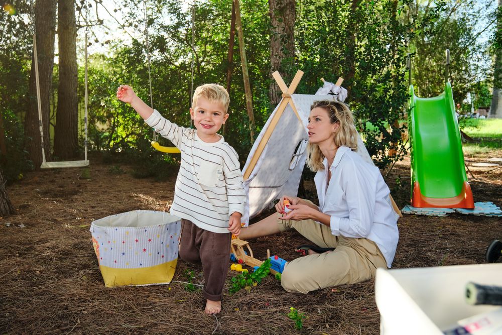 Happy boy with mother playing near tent in park