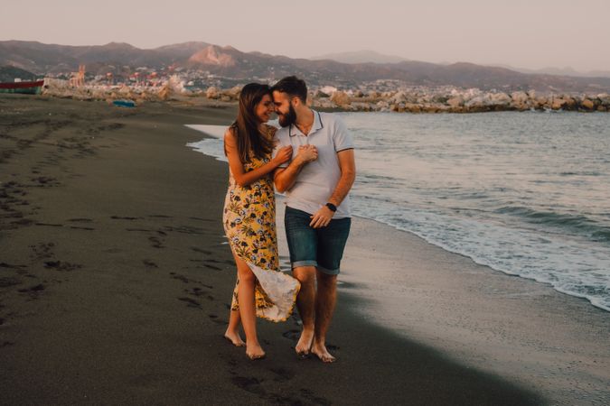 Lovely couple walking holding hands on sandy beach