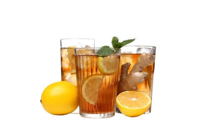 Glasses of cold tea with orange and ginger, isolated on plain background
