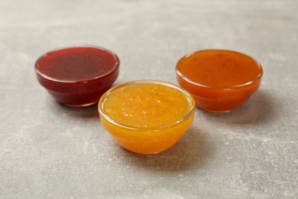 Bowls with jam on gray background, close up