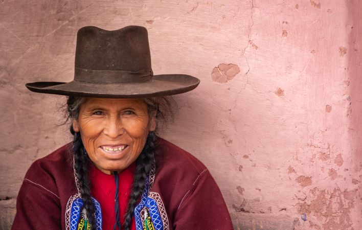 Peru - January, 02 2012: Peru - Peruvian woman sitting near stone wall