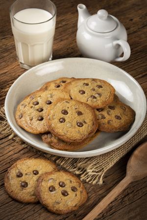 Delicious chocolate cookies with glass of milk on wooden table.