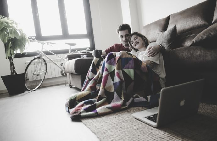Couple wrapped in plaid watching laptop