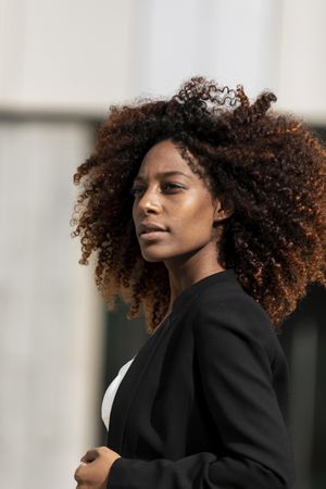 Black female standing outside of cement building in the sunshine