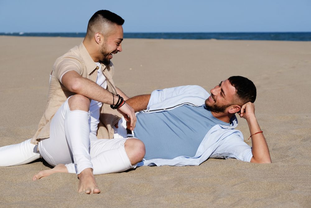 Affectionate gay couple relaxing on beach