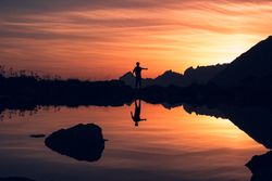 Person standing on shore and reflecting in water