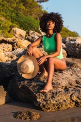 Black woman in swimsuit and with hat on beach