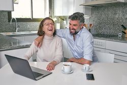 Mother and adult son laughing over video on laptop
