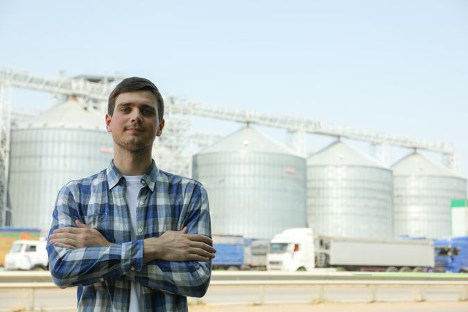 Young man against grain silos. Agriculture business