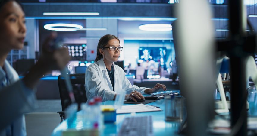 Medical Research Center Laboratory: White Female Neurologist Using Desktop Computer With MRI And PET Scans Of a Brain.