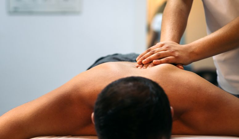 Young woman treating a male patient. back massage physiotherapy. close-up. front view