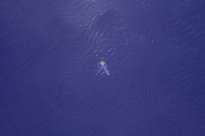 Far away aerial image of woman swimming in purple water