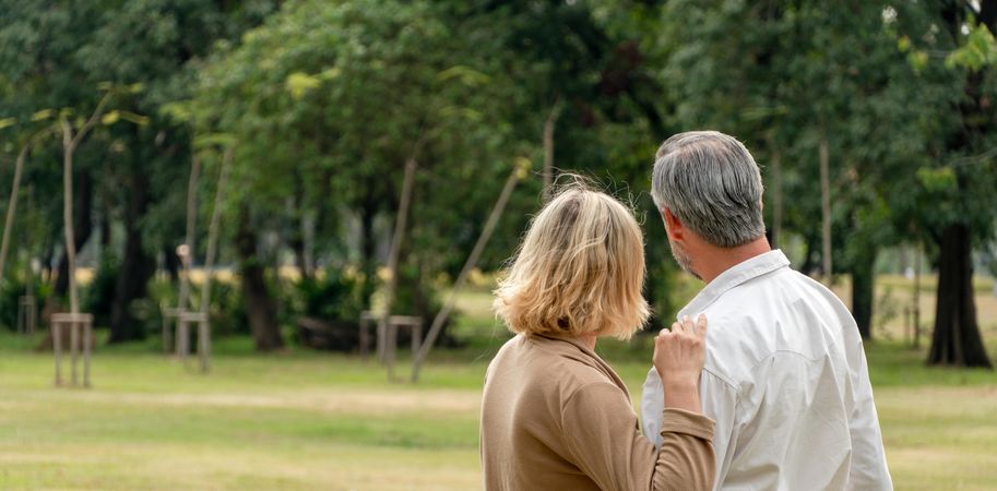 Wide shot of mature man and woman standing in park