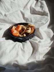 Bowl of orange slices, cashews and pancakes in morning light
