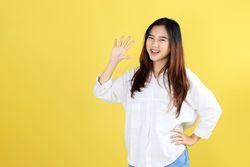 Friendly Asian Female Student Saying Hello, Waving Raised Hand to Say Hi