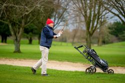 Man swinging club on golf course