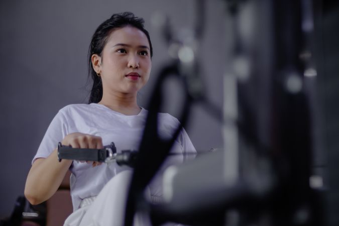 Concentrated young woman working out on rowing machine indoors