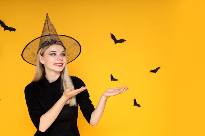 Concept of Halloween, young woman on yellow background