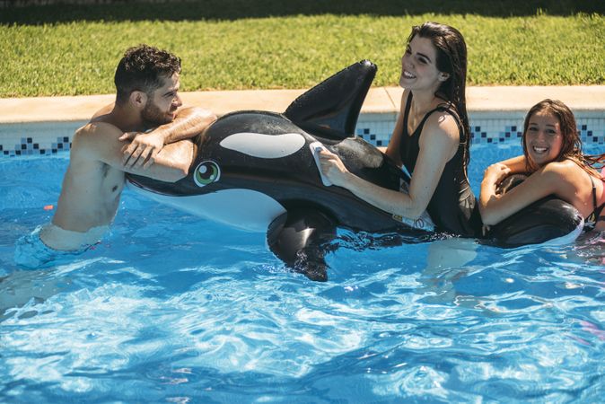 Happy friends with toy in pool