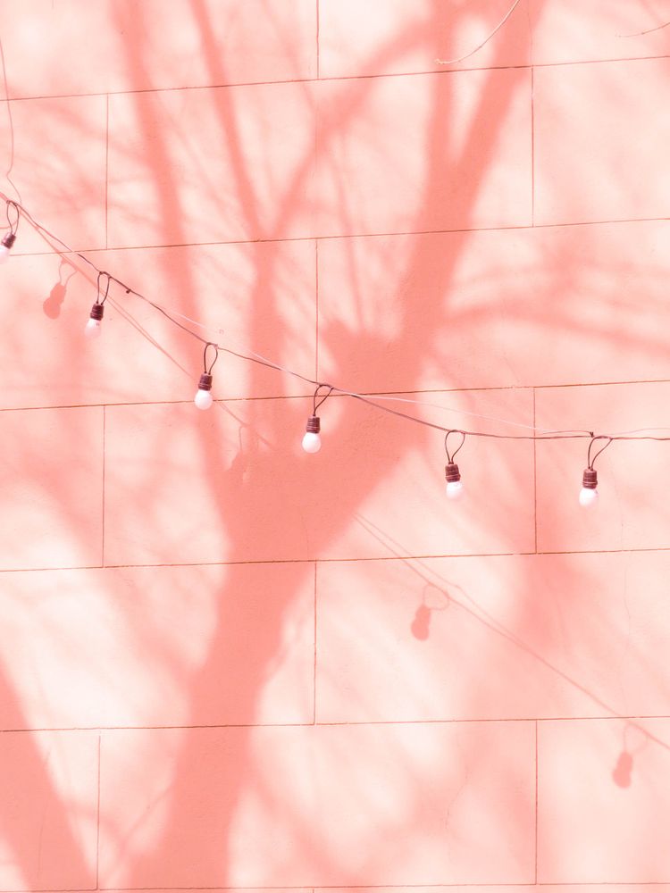 String light beside wall with tree shadow