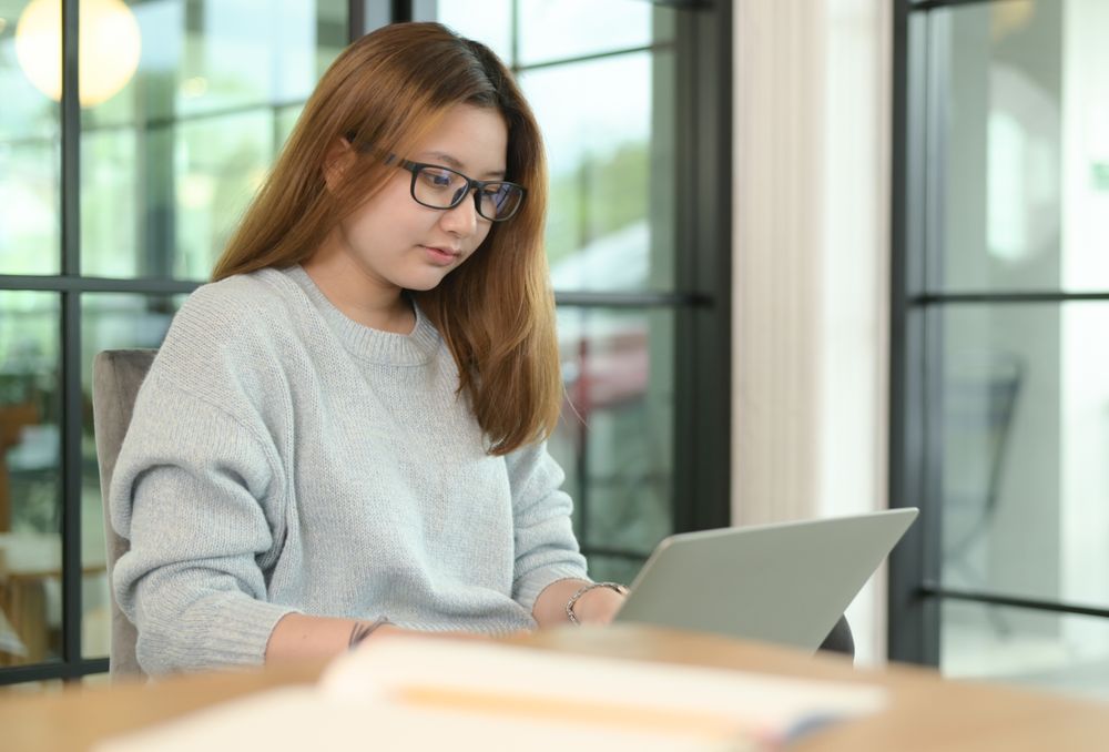 Woman sitting comfortably looking at laptop screen.