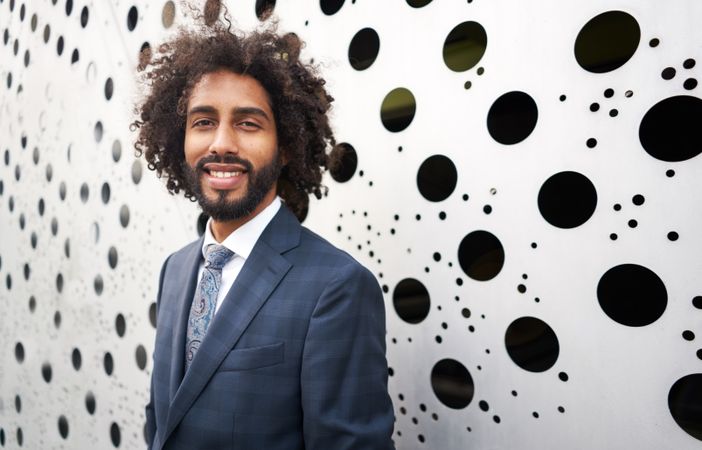 Cheerful entrepreneur standing next to wall