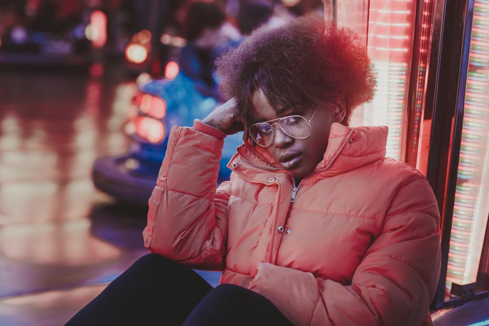 Black female sitting near attraction in amusement park