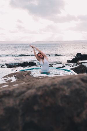 Woman sitting in pool near stones