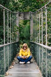 Happy female traveler taking selfie on suspension bridge in summer