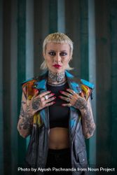 Young punk hipster woman with short blonde bangs poses in vest with full sleeve tattoos beXP34