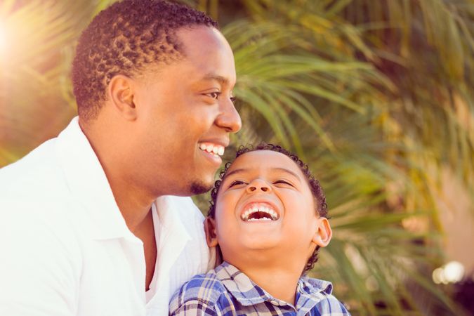 Black Father Smiling With Son Outdoors