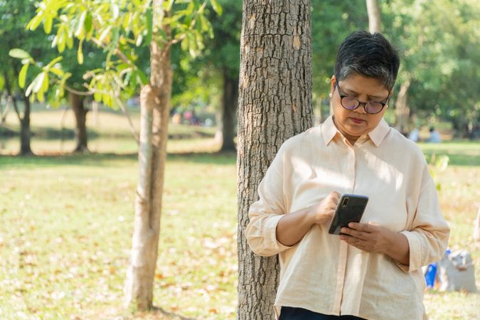 Older Asian woman checking smart phone in park
