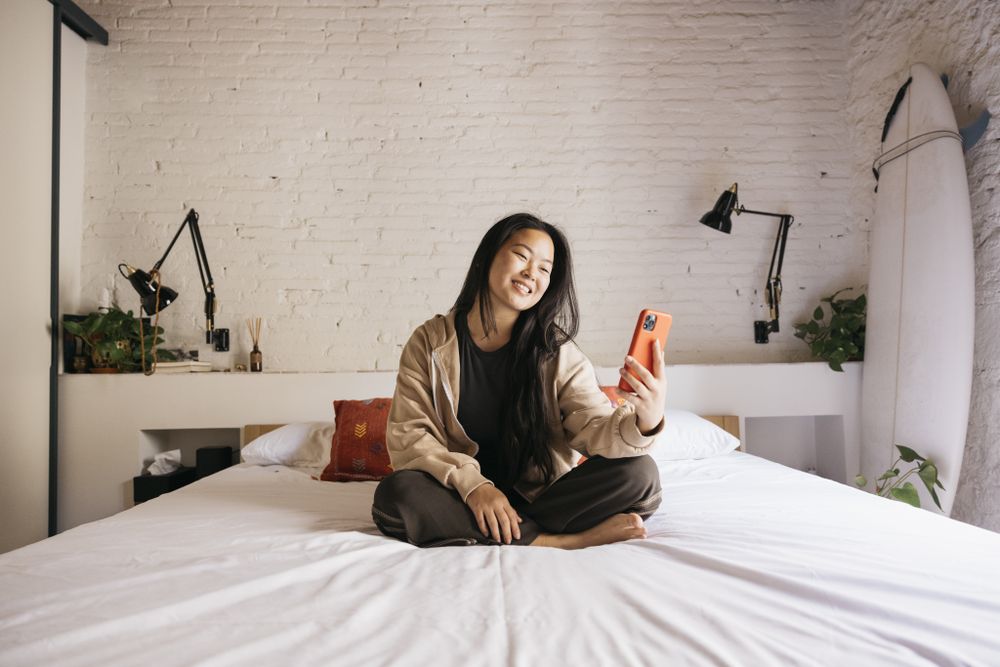 Young female with a phone on bed