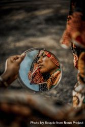 Side view of woman in colorful headscarf reflection on round mirror 5RzM25