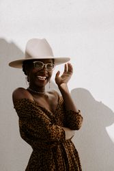 Smiling woman in brown dress with fedora hat