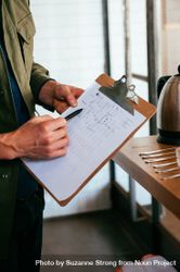 Man’s hands pointing at a chart on a clipboard at coffee facility 41lY75