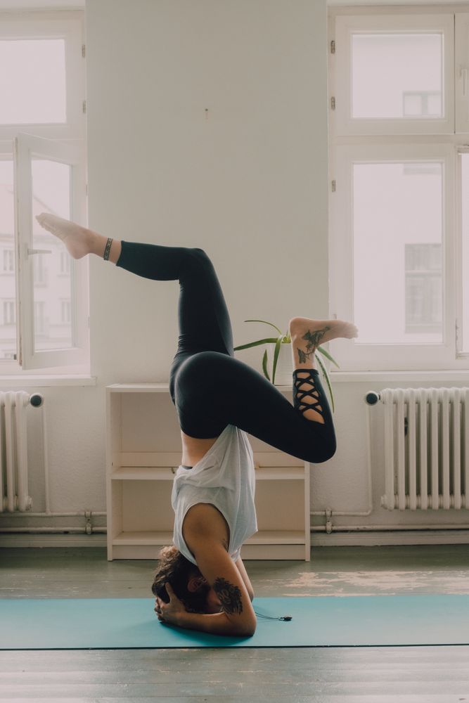 Fit woman practicing yoga pose and standing on head at home
