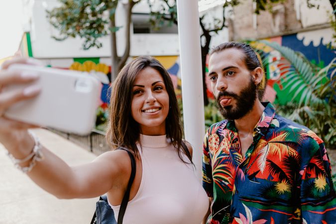 Trendy couple taking selfie on city street