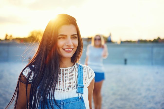 Portrait of content brunette woman with friends in background on beach