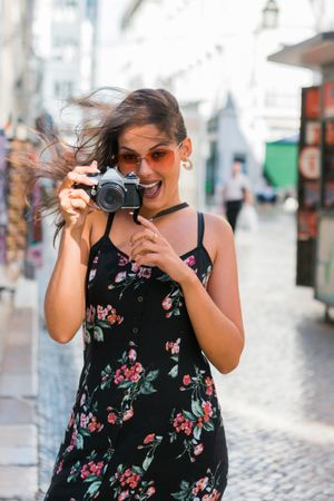 Casual woman taking photo with camera while standing on street