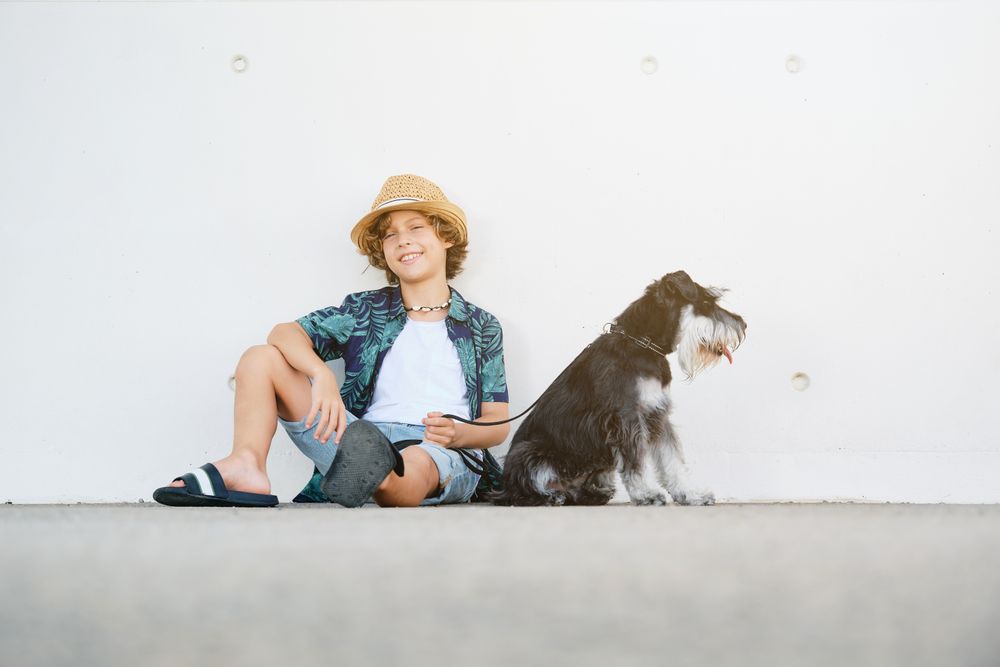 Smiling child with dog sitting against wall