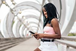 Portrait of a Black young woman enjoying the summer in the city using smartphone