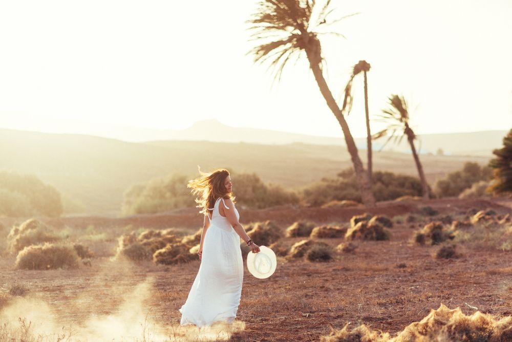 Woman in white dress in dry field in sunlight